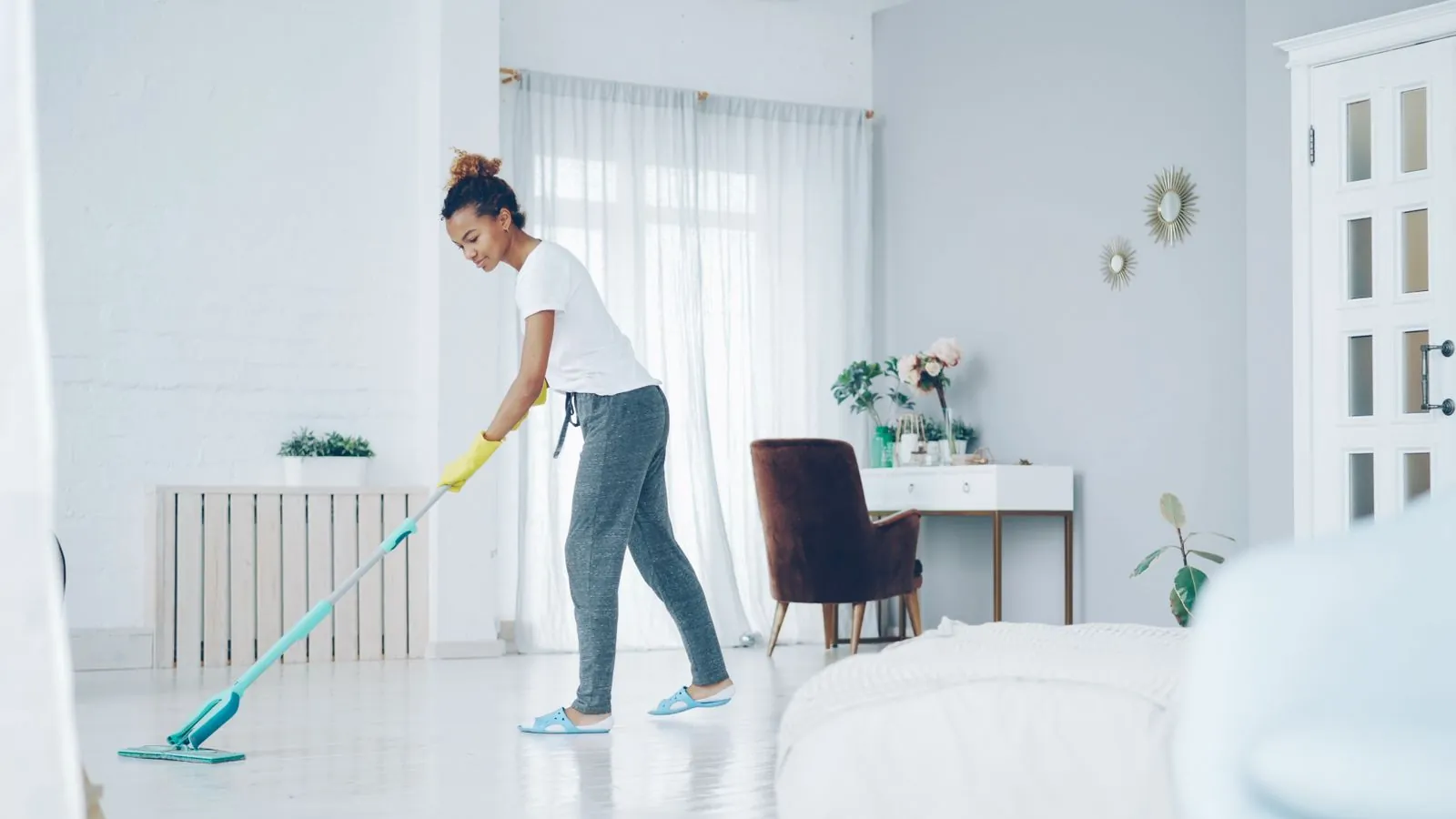 Cleaner mopping the floor of a bright, open living room